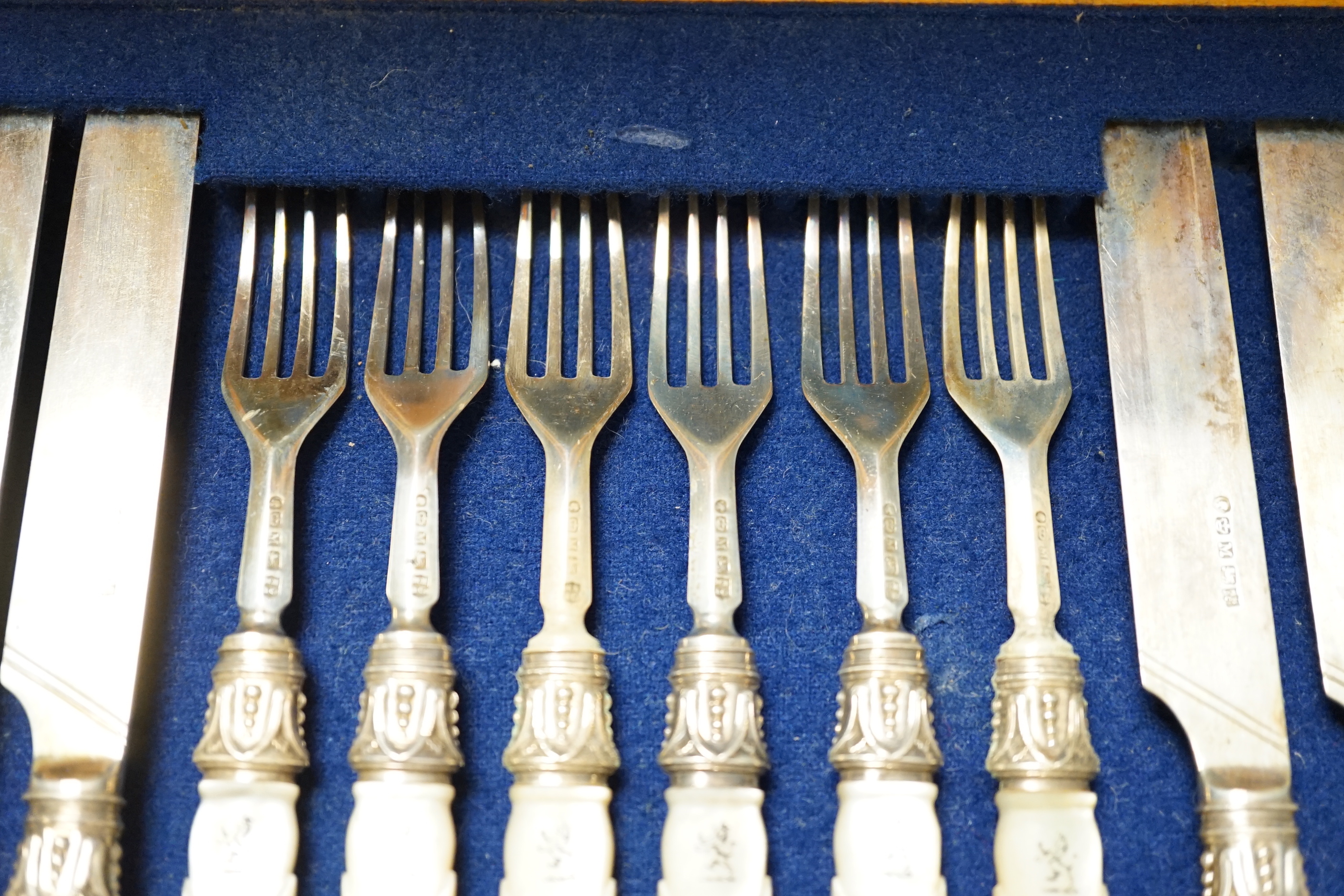 A Victorian cased set of twelve pairs of silver dessert knives and forks, with crested carved mother of pearl handles, Sheffield 1855